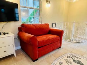 a red chair in a living room with a tv at Beachside Historic Cottage - Steps to Sand! in Clearwater Beach