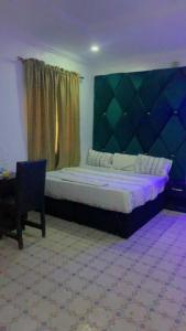 a bedroom with a bed and a chair and a window at Blue Moon Hotel Victoria Island in Lagos