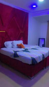 1 dormitorio con 1 cama grande y cabecero rojo en Blue Moon Hotel Victoria Island, en Lagos