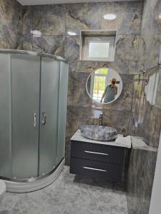 a bathroom with a shower and a sink and a mirror at Отель яблоневый сад in İsmayıllı
