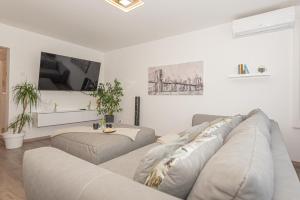 a living room with a couch and a tv at Apartman Holiday in Šibenik