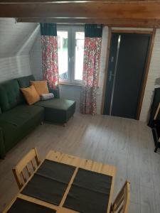 uma sala de estar com um sofá verde e uma mesa em domek good vibes B em Gnieżdżewo