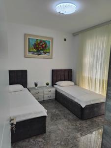 a bedroom with two beds and a painting on the wall at Отель яблоневый сад in İsmayıllı