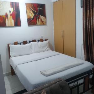 ナイロビにあるRacecourse one bed apartment ngong Roadの白いシーツと枕が備わったベッドのある寝室 +5枚の写真