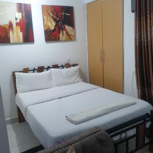 1 dormitorio con 1 cama con sábanas y almohadas blancas en Racecourse one bed apartment ngong Road, en Nairobi