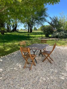 een houten picknicktafel en twee stoelen in een park bij Domaine des quatre terres in Lesparre-Médoc