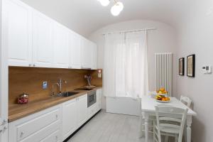 a kitchen with white cabinets and a sink and a table at Colosseo House in Rome