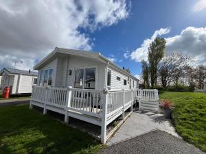 a white tiny house with a white porch at Kestral Court Lodge, Scratby - California Cliffs, Parkdean, sleeps 6, bed linen and towels included, wrap around decking - no pets in Scratby