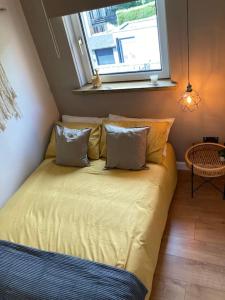 a bed with pillows and a window in a room at Rustic Top Floor West End Pad With Balcony, Parking next to Byers Road, Aston Lane, Glasgow Uni in Glasgow