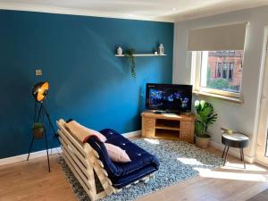 Una sala de estar con paredes azules y un sofá y un televisor. en Rustic Top Floor West End Pad With Balcony, Parking next to Byers Road, Aston Lane, Glasgow Uni, en Glasgow