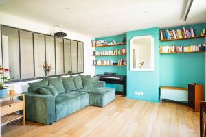 ein Wohnzimmer mit grüner Couch und blauen Wänden in der Unterkunft Duplex entier - Pantin in Pantin