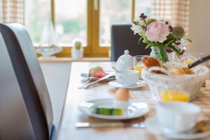 una mesa con un plato de comida y un jarrón de flores en Reethaus am Deich en Dierhagen