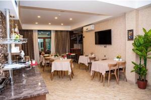 a restaurant with tables and chairs and a flat screen tv at Sebail Inn Hotel in Baku