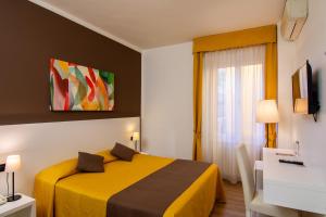 a hotel room with a yellow bed and a window at Hotel Eden Salò in Salò