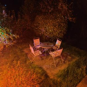 three chairs and a table in the grass at night at Entire 3 bed house/free private parking, garden in Falmer