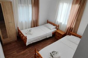 two beds in a small room with white sheets at Dafnonas House - Bright & Modern in Leonidion