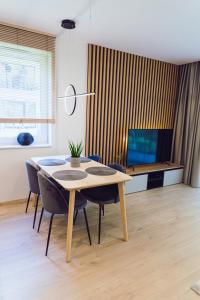 a dining room with a table and chairs and a television at Nice River Apartment in Ostróda