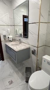 a white bathroom with a sink and a toilet at Firdavsi Hotel in Dushanbe