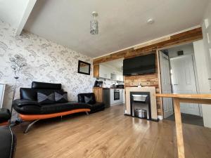 a living room with a black couch and a kitchen at Signature, Scratby - Two bed chalet, sleeps 7, free Wi-Fi, free entry to onsite clubhouse - no pets in Scratby