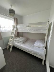 a bedroom with two bunk beds and a ladder at Signature, Scratby - Two bed chalet, sleeps 7, free Wi-Fi, free entry to onsite clubhouse - no pets in Scratby