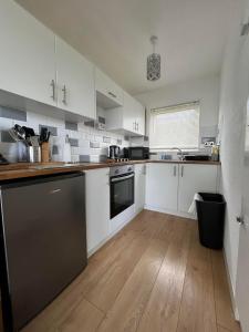 a kitchen with white cabinets and a black dishwasher at Signature, Scratby - Two bed chalet, sleeps 7, free Wi-Fi, free entry to onsite clubhouse - no pets in Scratby