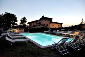 einen Pool mit Liegestühlen und ein Haus in der Unterkunft Comfortable apartment in the heart of the Tuscan countryside in Pulicciano
