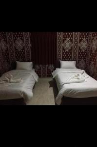 two beds in a room with white blankets on them at Wadi rum moon camp in Disah