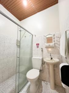 a bathroom with a toilet and a shower and a sink at Pousada Vila do Penedo in Penedo