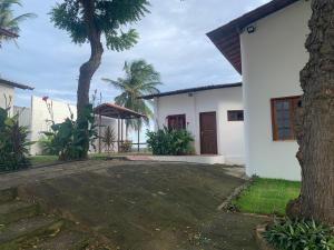 a white house with a tree and a courtyard at Morro Branco Suítes - Hospedaria Morro Branco in Beberibe