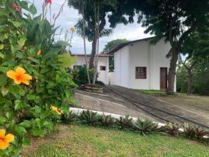 une maison avec une cour fleurie devant elle dans l'établissement Morro Branco Suítes - Hospedaria Morro Branco, à Beberibe