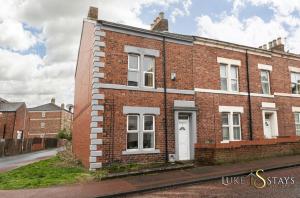 a brick building with a white door on a street at Luke Stays - Granville Street in Gateshead