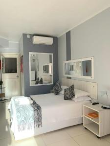 1 dormitorio con 1 cama blanca grande y espejo en Pousada Krolow, en Pelotas