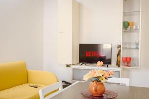 Una sala de estar con una mesa con un jarrón de flores. en PINK BARBIE'S HOUSE, Domus Lumeras, en Alghero