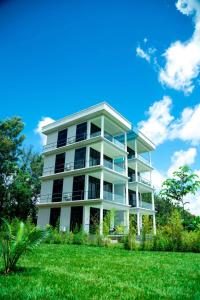 um edifício de apartamentos branco com um relvado verde em Shose Farm House em Shiri