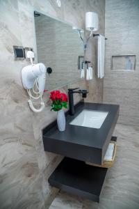 a bathroom with a sink with a vase of flowers at Shose Farm House in Shiri