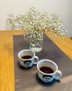 duas chávenas de café numa mesa com um vaso de flores em Apartma Srečko, Sežana em Sežana