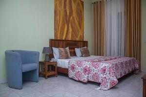a bedroom with a bed and a blue chair at Résidence GESAM in Sabalibougou