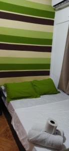 a bed with a green and white striped wall at Ofiuras Hostal in Colón