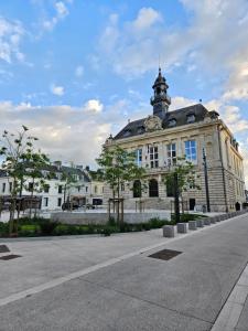 un grand bâtiment avec une tour au sommet dans l'établissement Charmant Duplex au cœur de Vernon proche gare et Giverny, à Vernon