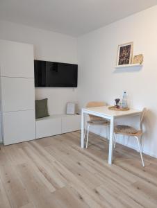 a white dining room with a white table and a tv at Fuchsbau in Schleiden