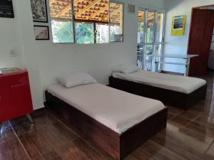 een kamer met 2 bedden, een tafel en ramen bij Sítio na Mata Atlântica in Tapiraí
