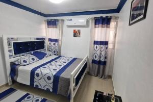 1 dormitorio con cama y cortinas azules y blancas en Lujosa y espaciosa Villa María. en Santiago de los Caballeros