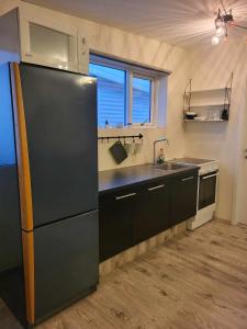 uma cozinha com um frigorífico preto e um lavatório em Vallholt em Selfoss