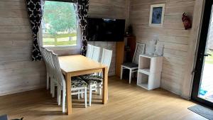 a dining room with a table and chairs and a television at Domki wypoczynkowe LAS in Śliwice