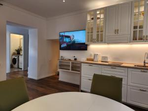 a kitchen with white cabinets and a flat screen tv at Villa Marina Izola - Free Parking in Izola