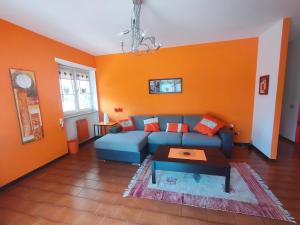 アオスタにあるLa Betulla Appartamento confortevole Wifi e Parking freeの青いソファとオレンジ色の壁が備わるリビングルーム