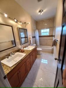łazienka z 2 umywalkami, toaletą i lustrem w obiekcie Kolibri Central Villa w mieście The Bight Settlements
