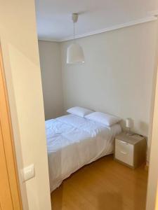 Habitación blanca con cama y mesita de noche en Pisito del Sol en Santander
