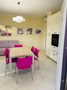 une cuisine et une salle à manger avec une table et des chaises roses dans l'établissement APARTAMENT GARDEN-MARINA SVEVA, à San Salvo