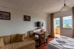 a hotel room with a couch and a table with a television at Evropa Lux Apartments in Budva